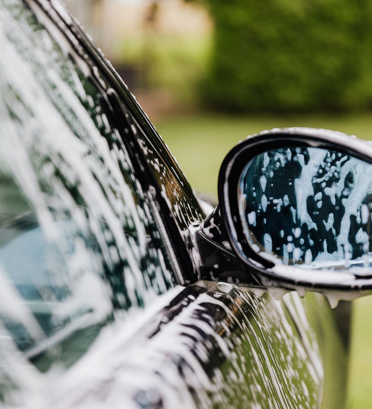 Sedan being hand washed with foam suds and water droplets